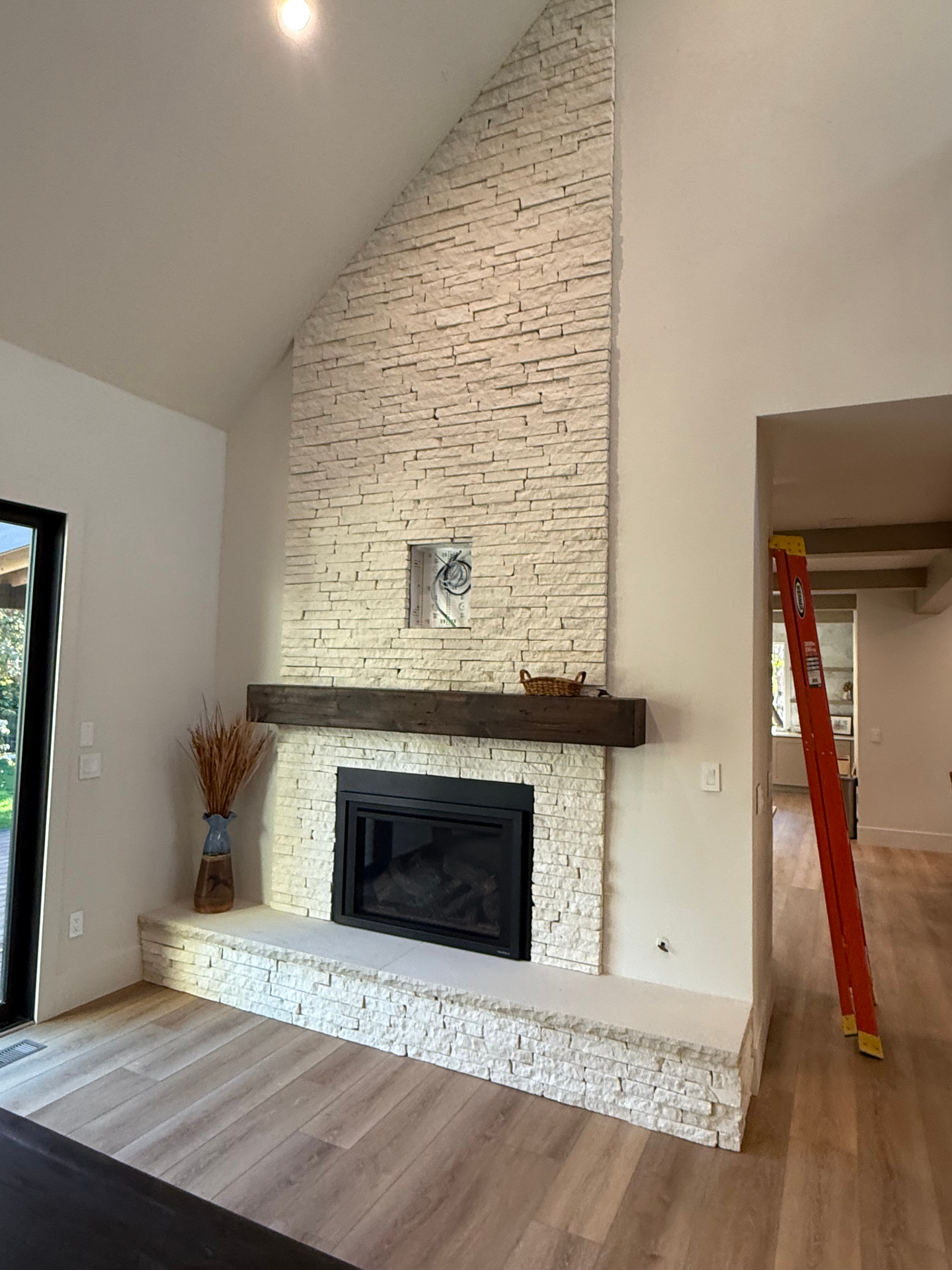Vaulted stacked-stone fireplace with reclaimed wood mantel